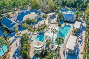 An aerial view of a resort with multiple swimming pools, a water slide, and lounge areas surrounded by palm trees. - Lakefront | Private Pool | LSV (Santa Rosa Beach)