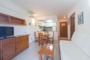 A living room with a TV, wooden cabinet, dining table, and chairs. - Royal Apartments Salou (Salou)