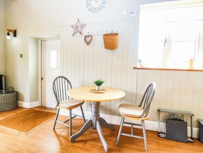 A dining area with a round table, two chairs, a small plant, and a star decoration on the wall. - Horseshoe Stable (Dereham)