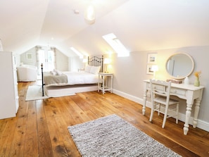 A bedroom with a bed, bedside tables, a dresser, a mirror, and a skylight. - Horseshoe Stable (Dereham)