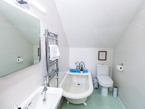 A compact bathroom with a bathtub, toilet, and sink. - Horseshoe Stable (Dereham)