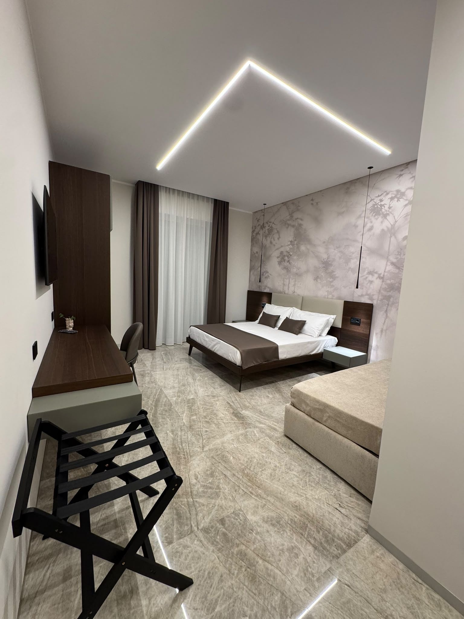Una camera d'albergo moderna con un letto, una scrivania e una zona salotto.