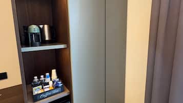 Camera d'albergo con angolo caffè integrato, comprensivo di macchina da caffè, bollitore e bancone con bevande e condimenti.