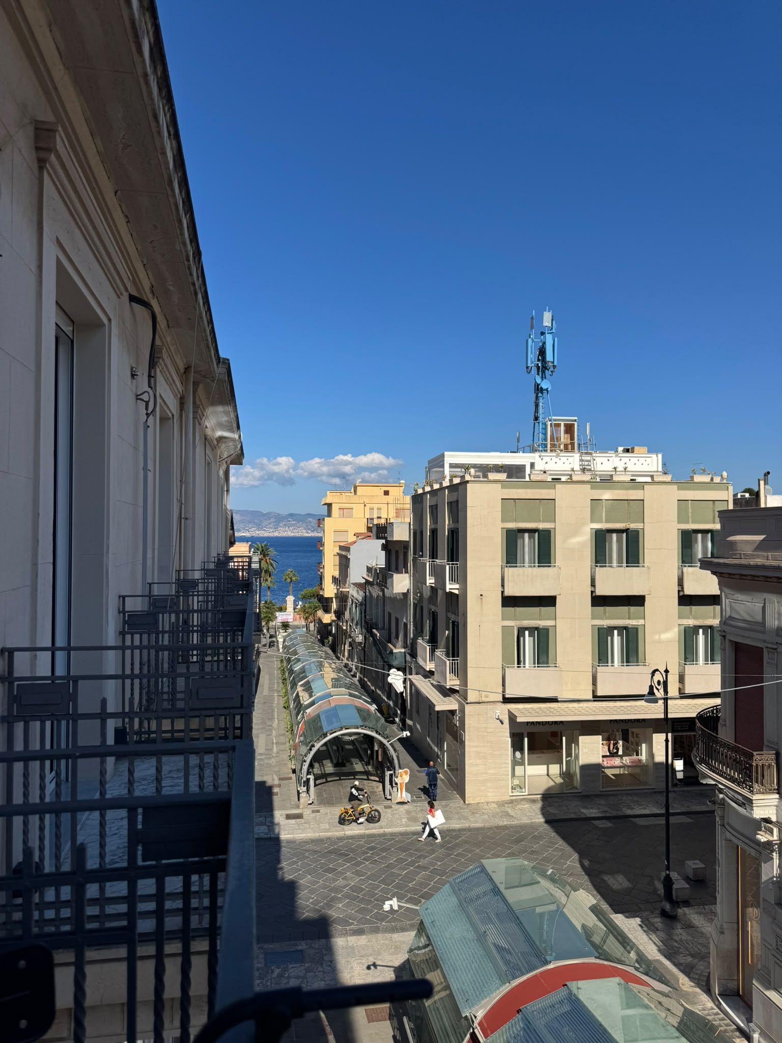 Une vue de rue avec des bâtiments, un ciel dégagé et une vue lointaine sur la mer.