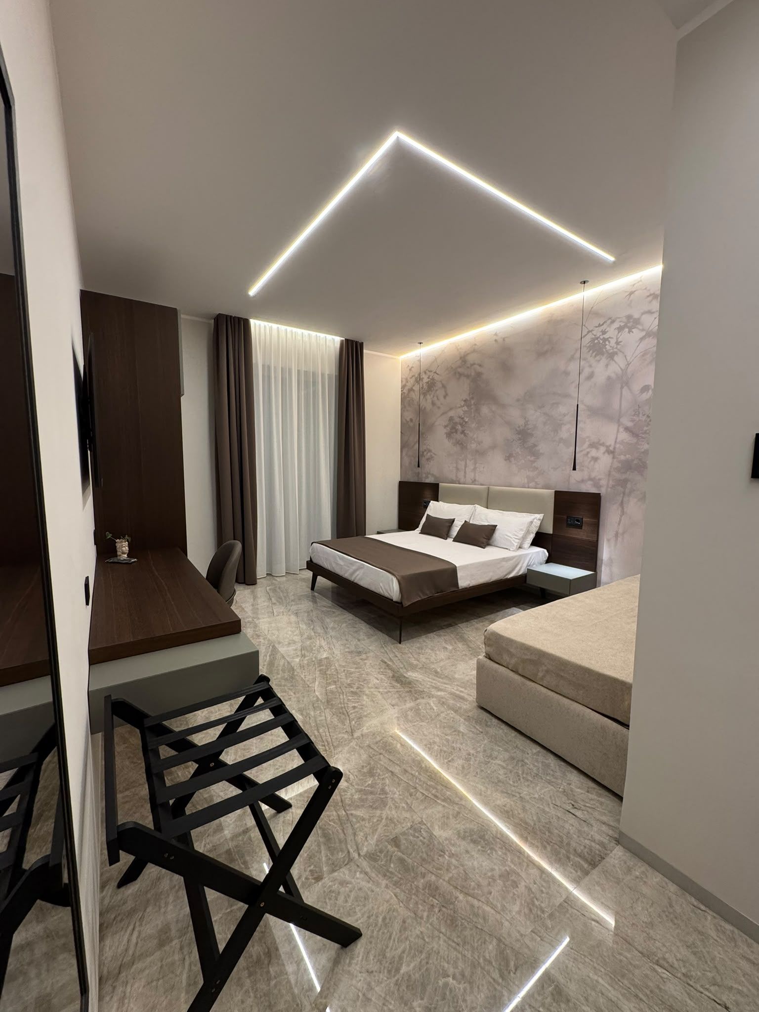 A modern bedroom with a bed, bedside tables, a desk, and a chair.
