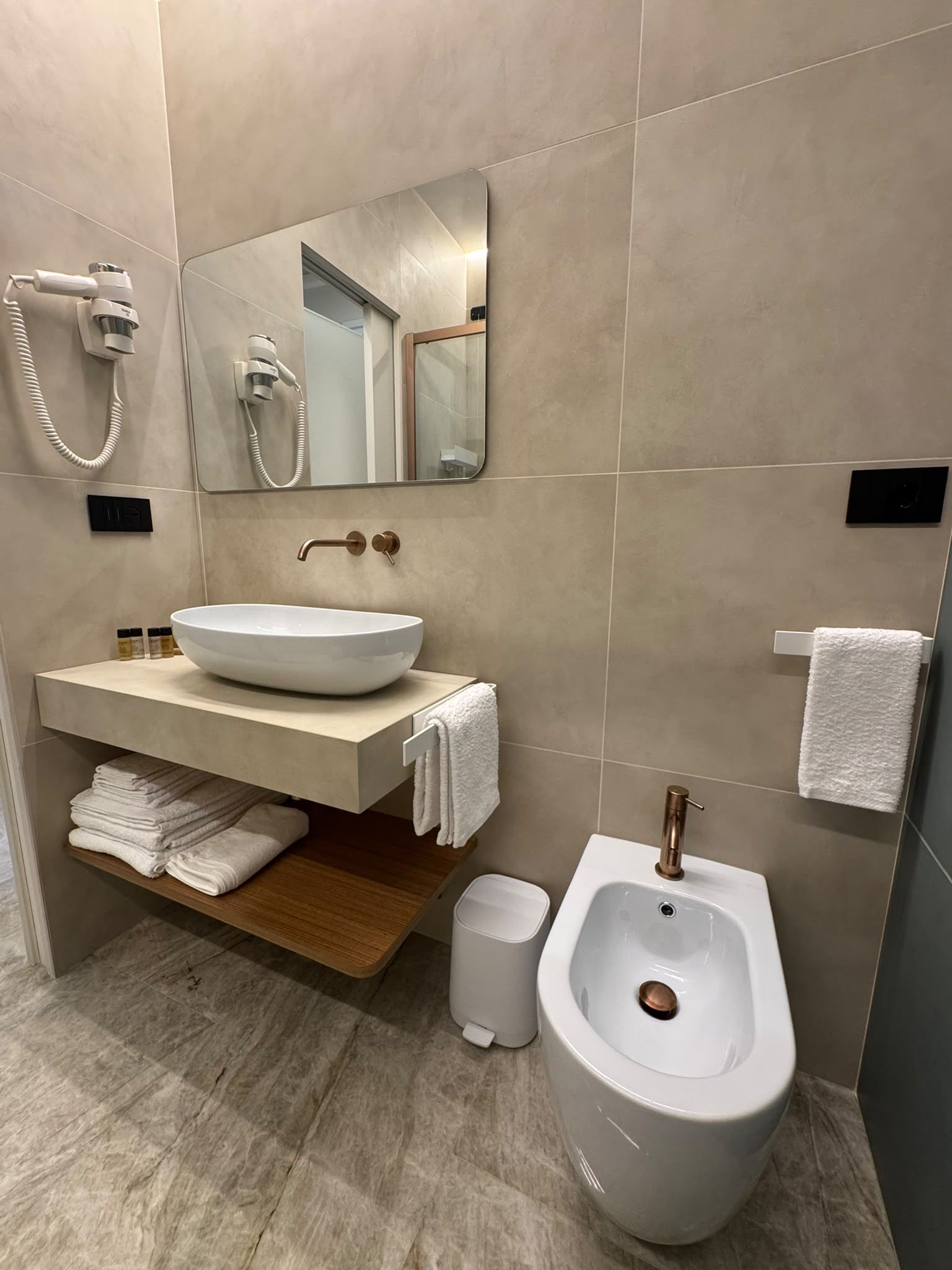 A modern bathroom with a large sink, a bidet, a mirror, and a towel rack.