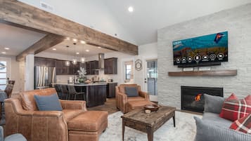Un salón moderno con sofás de cuero, una chimenea y un televisor grande montado en una pared de ladrillo blanco.