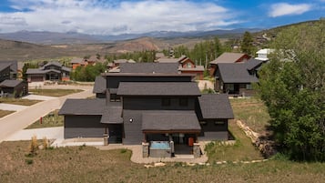 Una casa moderna de varios pisos con un amplio porche delantero y una piscina.
