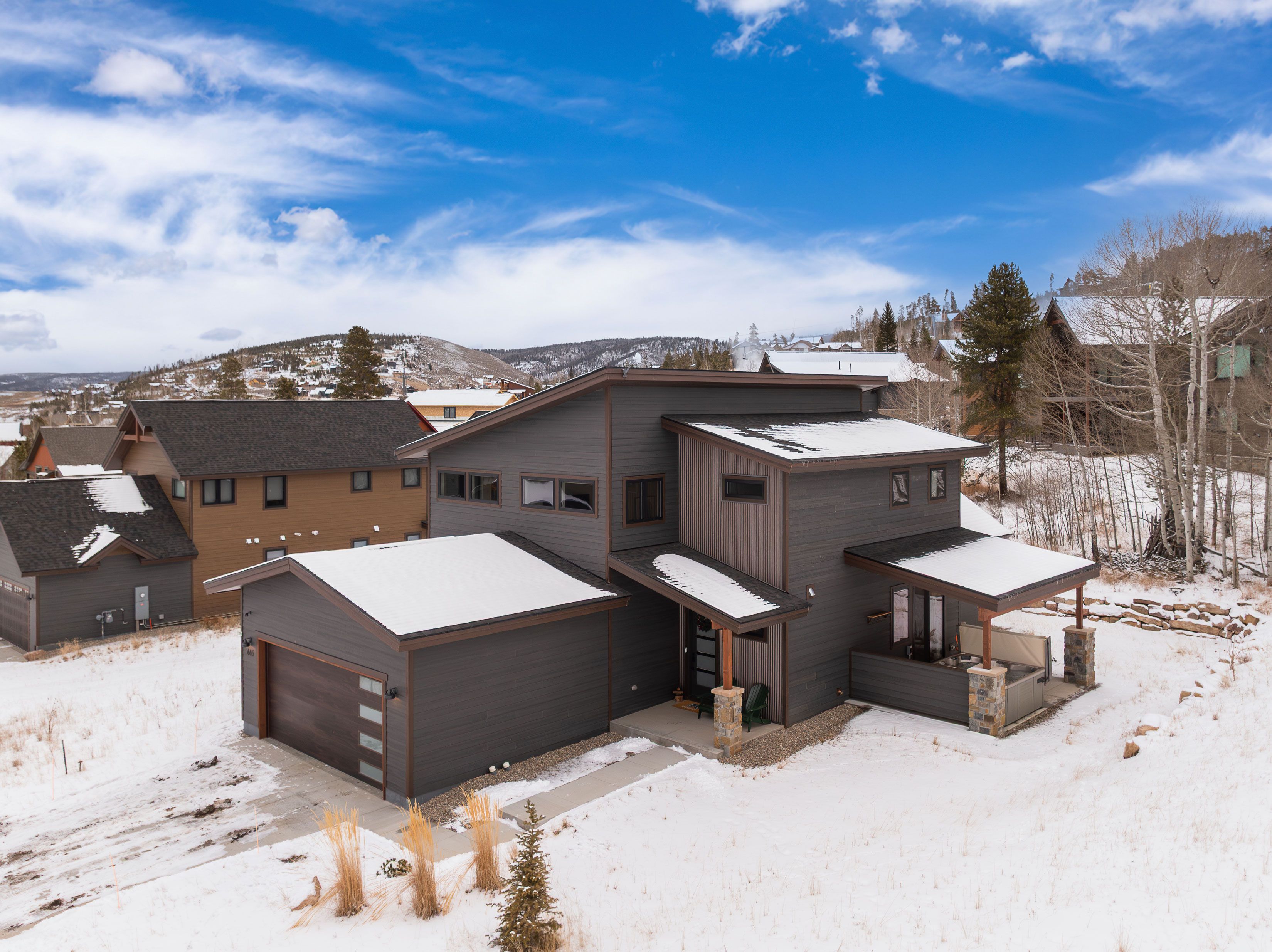 A modern multi-story residential building with a covered garage and a patio area.