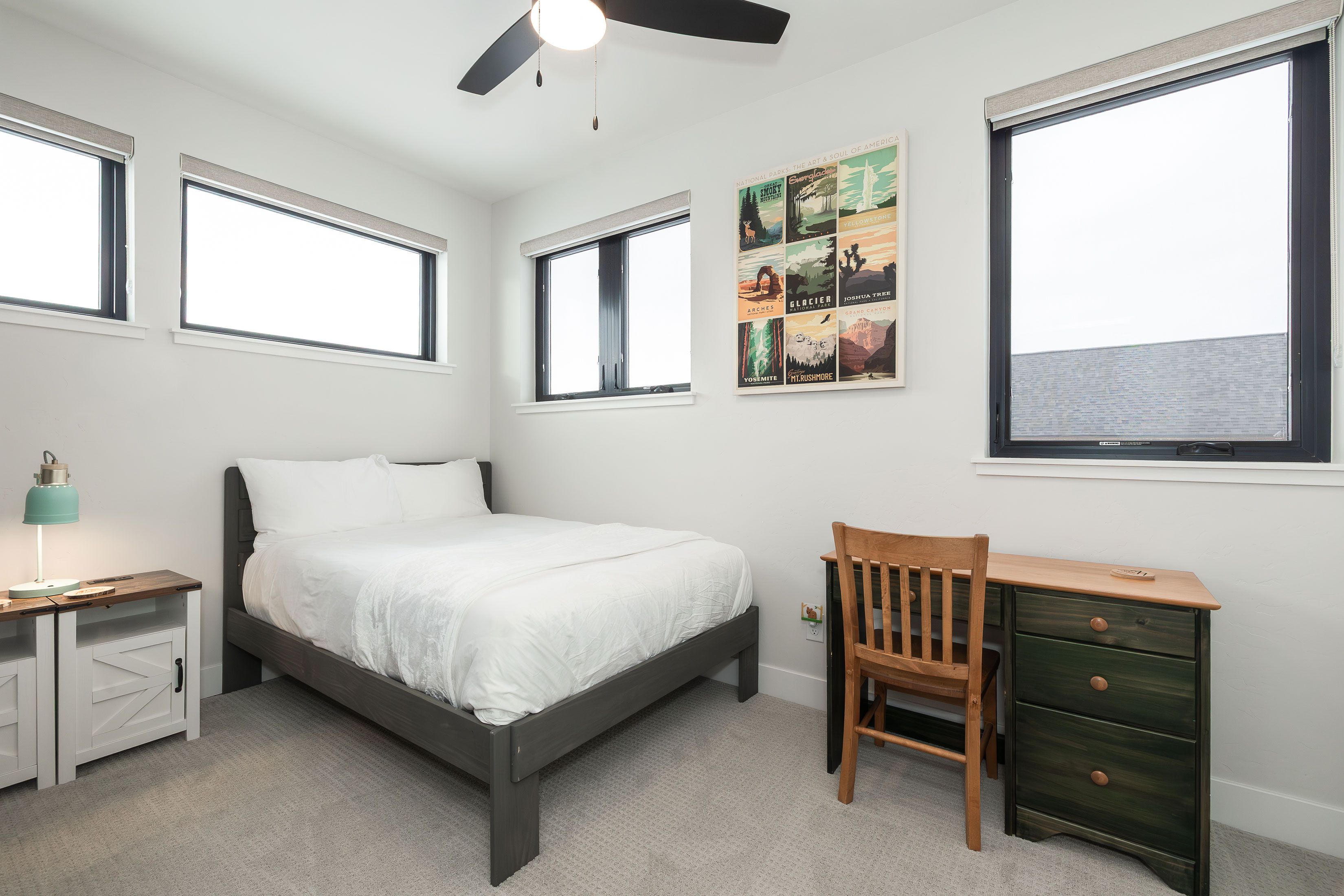 Un dormitorio con cama, escritorio, silla y ventilador de techo.