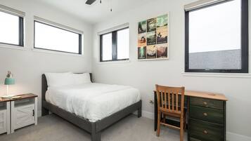 Un dormitorio con cama, escritorio, silla y ventilador de techo.