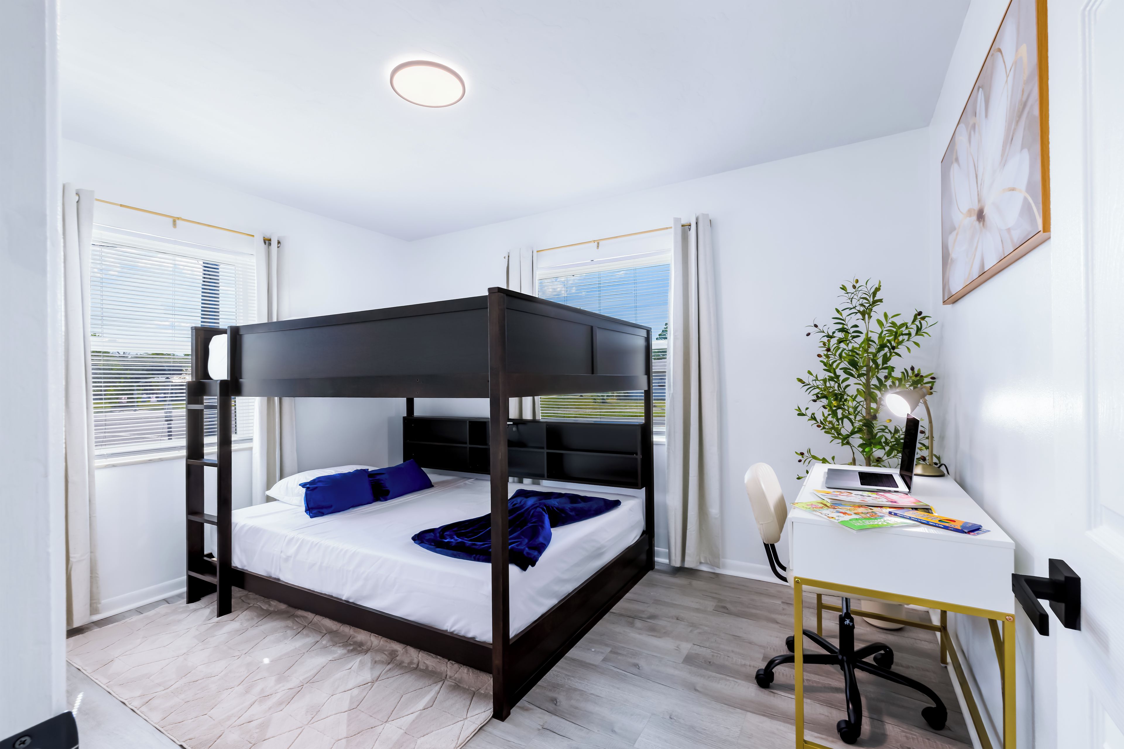 Een moderne slaapkamer met een hemelbed, een bureau met stoel en een raam met jaloezieën.