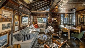 A cozy cabin interior with a wooden ceiling, a dining area, and a sofa with cushions. - Chalet La Renarde-a rare and unique 5-bedroom chalet near the centre of Chamonix (Chamonix-Mont-Blanc)