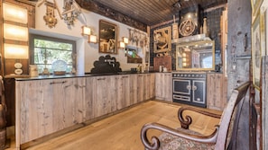 A rustic kitchen with wooden cabinetry, a vintage stove, and various kitchen utensils displayed on the wall. - Chalet La Renarde-a rare and unique 5-bedroom chalet near the centre of Chamonix (Chamonix-Mont-Blanc)