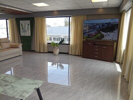 Una habitación amplia con un ventanal grande, un sofá, un armario y una mesa de mármol.