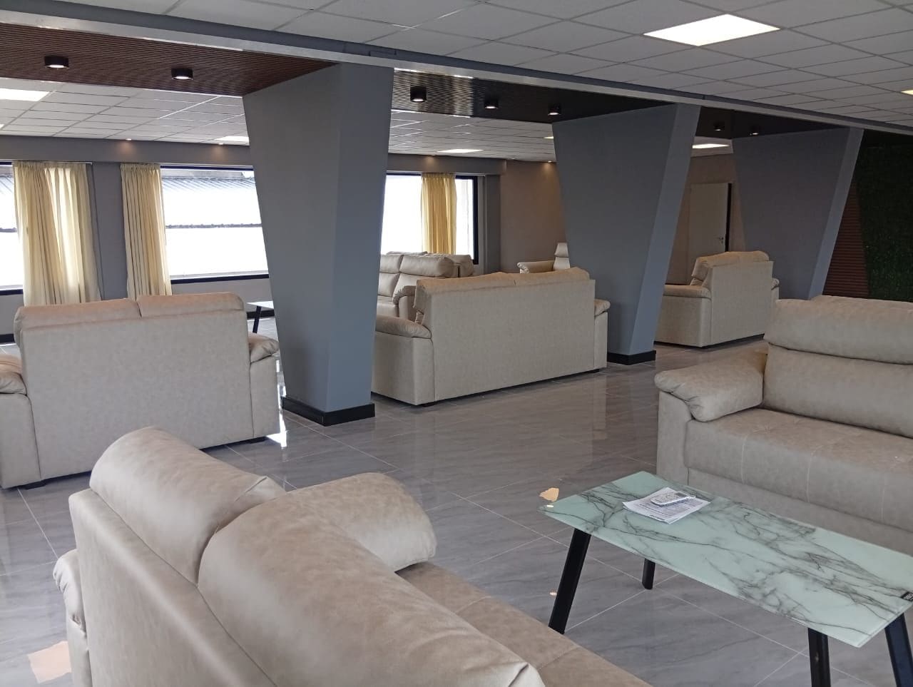 Un hall d’hôtel doté de plusieurs espaces salon, d’une table basse en marbre et de grandes fenêtres laissant entrer la lumière naturelle.