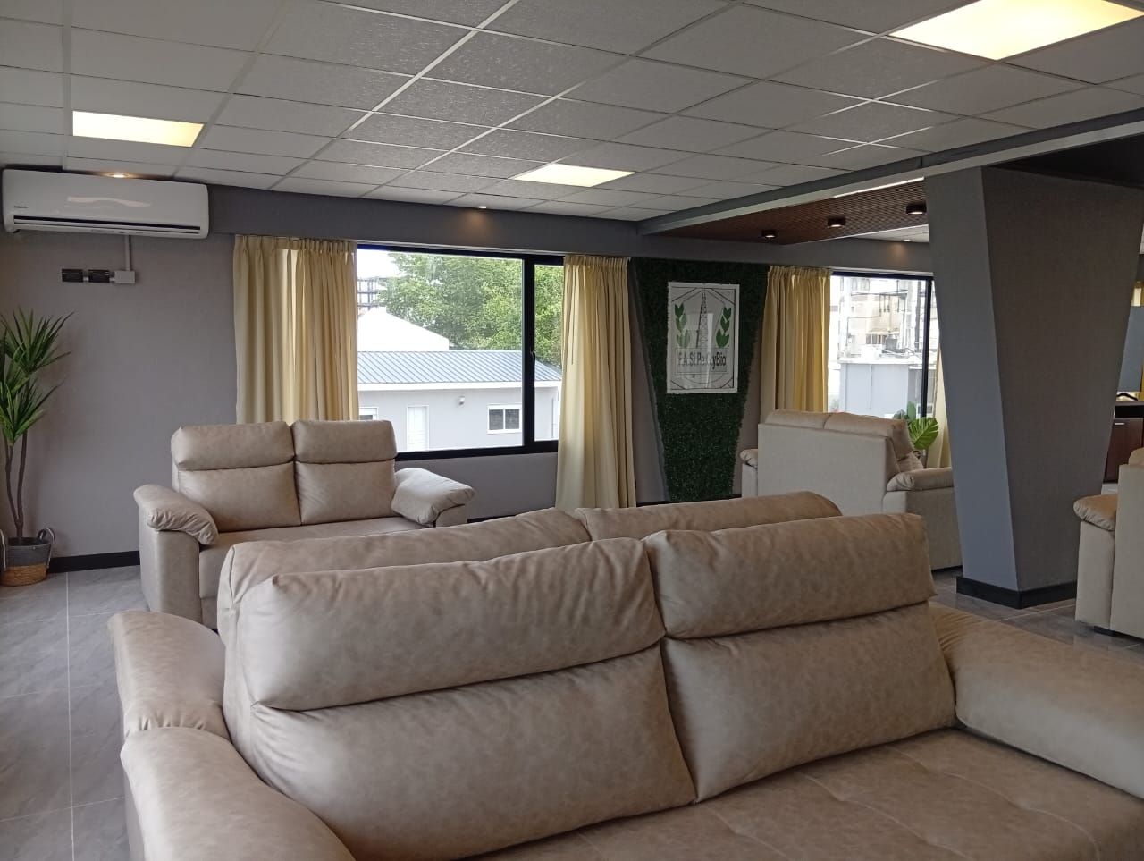 Un salon moderne avec un canapé beige, un fauteuil inclinable et une plante en pot.