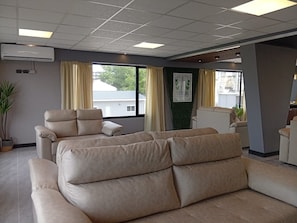 Un salon moderne avec un canapé beige, un fauteuil inclinable et une plante en pot.