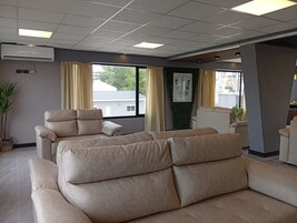 Una sala moderna con un sofá color crema, un sillón reclinable y una planta en maceta.