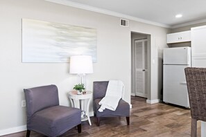 Un salon moderne avec un canapé, un fauteuil, une table d’appoint, une lampe et un tableau au mur.