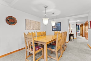 A dining area with a wooden table and chairs, a chandelier, and artwork on the walls. - Skiers' Paradise in Keystone | 4BR Luxury Retreat | Shuttle Steps Away (Keystone)