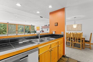 A modern kitchen with a large island, wooden cabinets, and a view of the outdoors. - Skiers' Paradise in Keystone | 4BR Luxury Retreat | Shuttle Steps Away (Keystone)