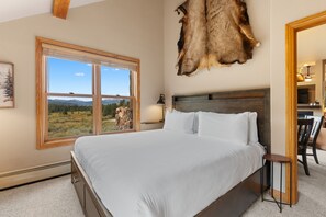A bedroom with a large bed, a window with a mountain view, a mounted animal hide, and a wooden headboard. - Keystone Getaway at Hidden River Lodge – Balcony Views & Shared Hot Tub (Keystone)