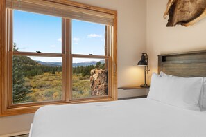 A bedroom with a large window, a bed, a nightstand, a lamp, and a wooden headboard. - Keystone Getaway at Hidden River Lodge – Balcony Views & Shared Hot Tub (Keystone)