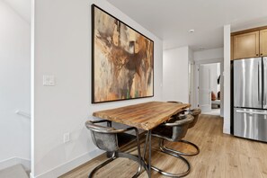 Eine moderne Küche mit einem Holztisch, Metallstühlen und einem Edelstahlkühlschrank.