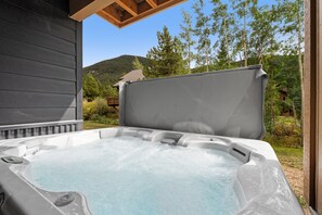Ein Whirlpool mit Holzterrasse und Blick auf bewaldetes Gebiet.