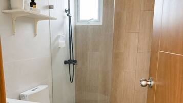 Un baño moderno con inodoro, cabina de ducha y lavamanos.
