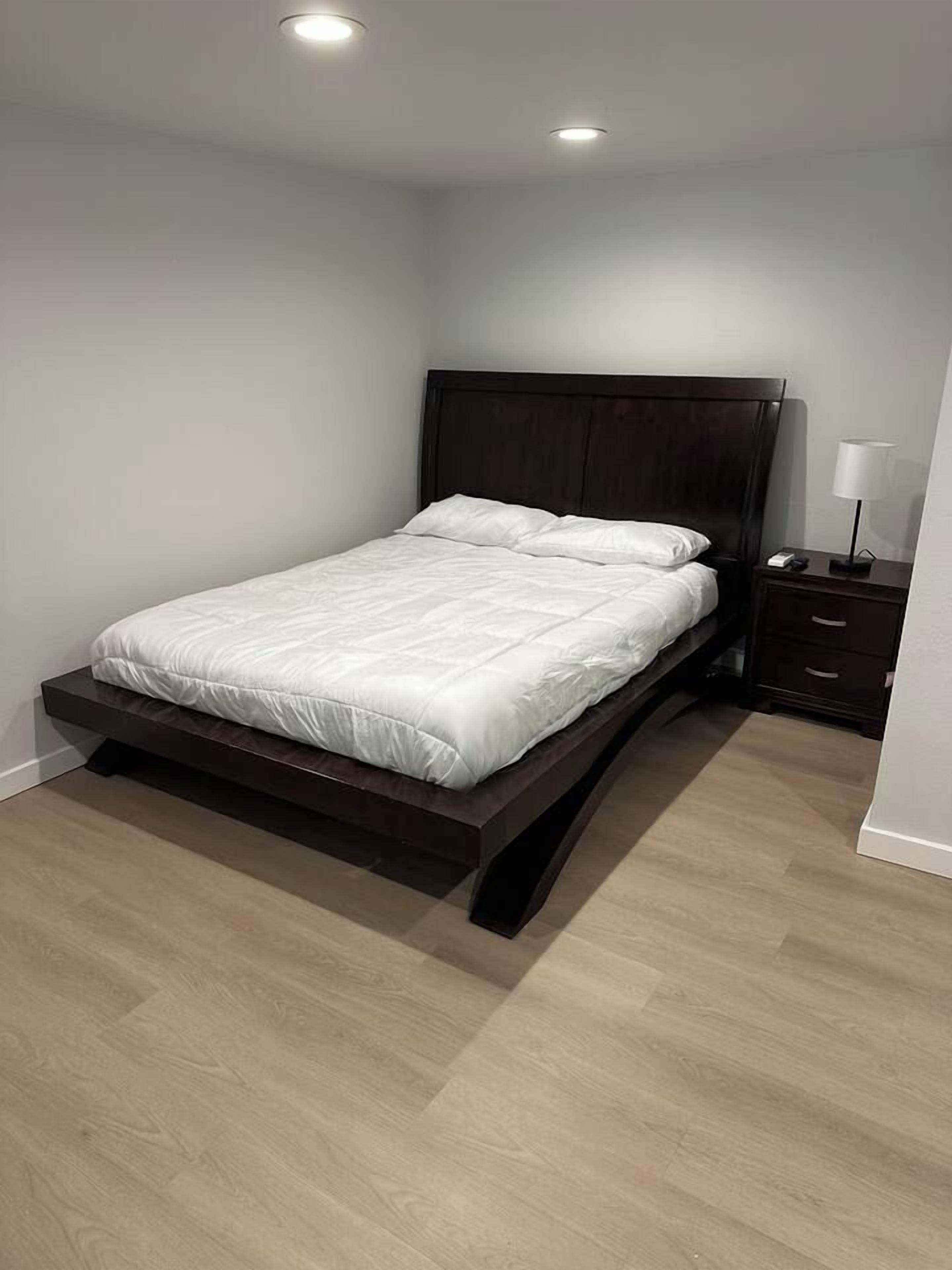 Une chambre à coucher avec un lit, une table de chevet et une lampe fixée au mur.
