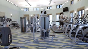 Ein Fitnessstudio mit Laufbändern, Krafttrainingsgeräten und Kurzhanteln.