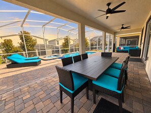 An outdoor patio with a pool, lounge chairs, and a dining table. - Family Paradise | 8BR | Champions Gate Resort (Kissimmee)