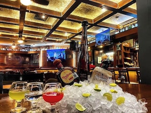 Una zona de bar con una botella de tequila Don Julio, hielo y vasos.