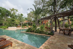 A pool area with a pergola, seating, and lush greenery. - Resort-Style 2-Bedroom | Padel, Pool, Grill, Coworking Space (Tulum)