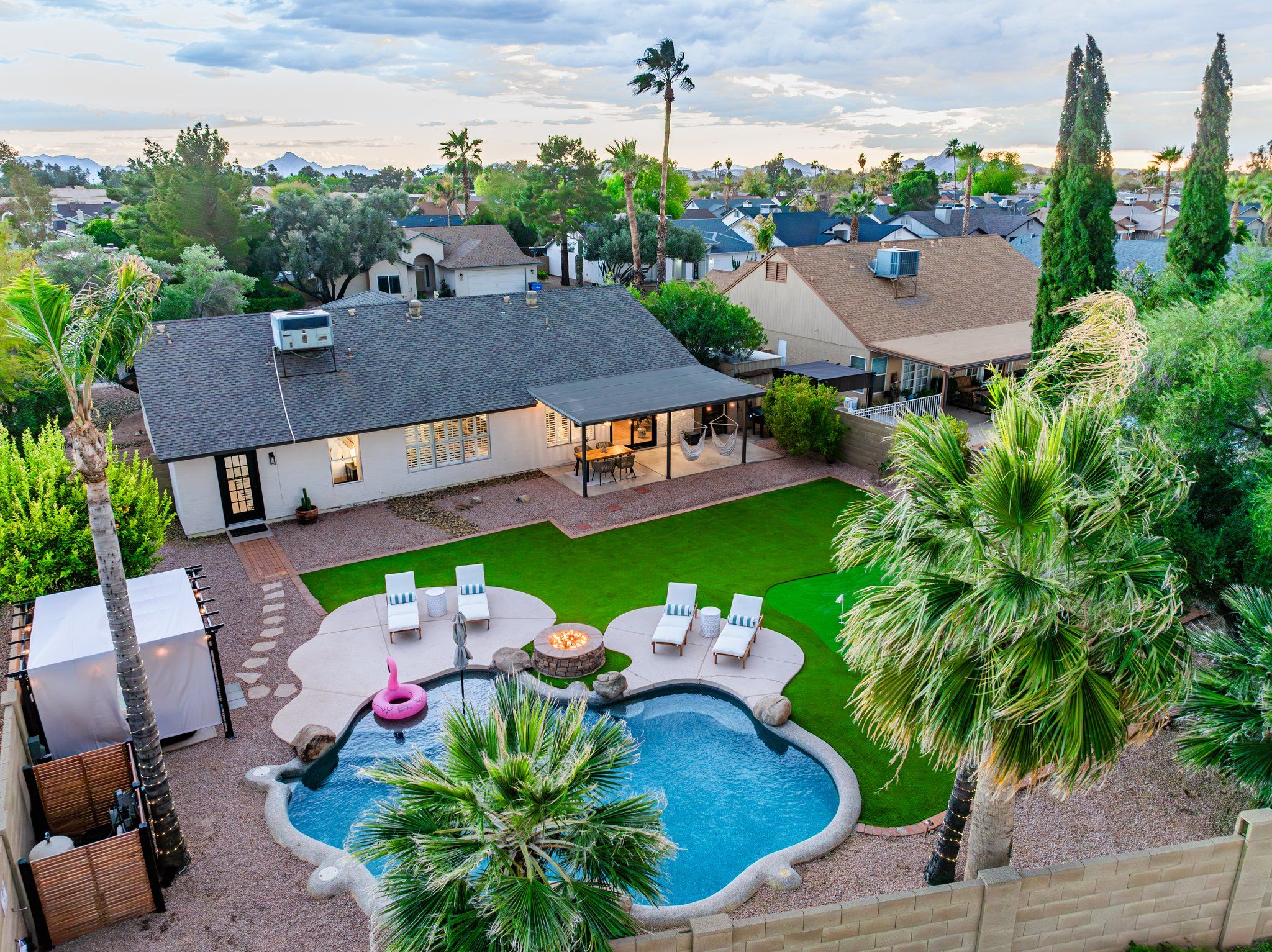 A residential property with a swimming pool, outdoor seating area, and a covered patio.