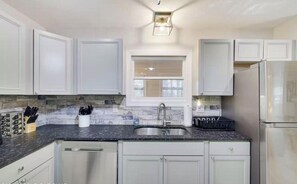 A kitchen with white cabinets, a granite countertop, a stainless steel sink, and a built-in dishwasher. - Cozy 3 BR Cottage-Walk to Lake-Minutes to Skiing-Make Lasting Memories (Pocono Lake)