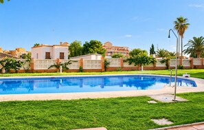 A swimming pool with a surrounding grassy area and a fence. - Coastal Family Apartment in Roquetas de Mar (Roquetas de Mar)
