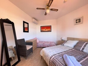 A bedroom with a bed, a chair, a dresser, a mirror, and a ceiling fan. - Coastal Family Apartment in Roquetas de Mar (Roquetas de Mar)