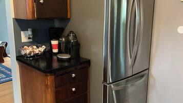 A compact kitchen with a stainless steel refrigerator, wooden cabinets, and a black countertop.