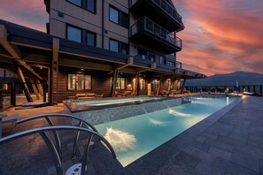 Ein modernes Hotel mit Dachpool, Sitzgelegenheiten im Freien und Blick auf die Berge.