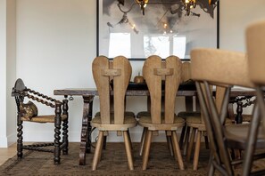 Ein Essbereich mit einem rustikalen Holztisch und -stühlen, einem gemusterten Teppich und einer Pendelleuchte.