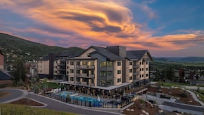 A modern hotel with multiple floors, a swimming pool, and a view of the surrounding landscape. - AMB107 | Newest Luxury Complex | Close to Gondola | Winter Shuttle | A/C (Steamboat Springs)