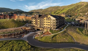 Un hôtel à plusieurs étages, doté d’un design moderne, situé sur une colline et offrant une vue sur les bâtiments et les collines environnantes.