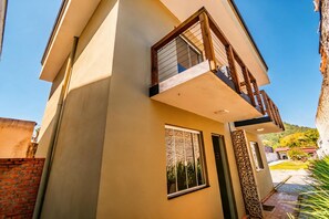 Ein modernes, zweistöckiges Gebäude mit Balkon, großen Fenstern und einer Ziegelwand.