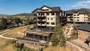 A multi-story building with balconies, a covered outdoor seating area, and a stone facade. - AMB109 | Newly Luxury Complex | Pool | Hot Tub | A/C | Winter Shuttle (Steamboat Springs)