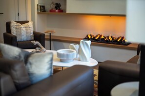 A modern living room with a fireplace, a sofa, and decorative vases. - AMB109 | Newly Luxury Complex | Pool | Hot Tub | A/C | Winter Shuttle (Steamboat Springs)