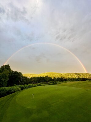 Un campo de golf con un arcoíris sobre el paisaje.
