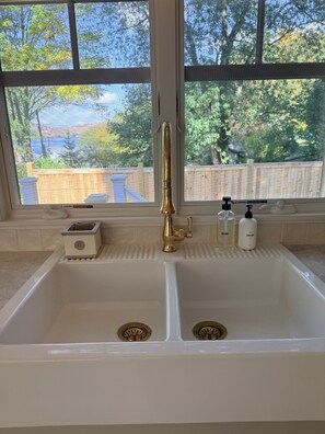 Un baño con lavamanos doble, grifo dorado y dos dispensadores de jabón.